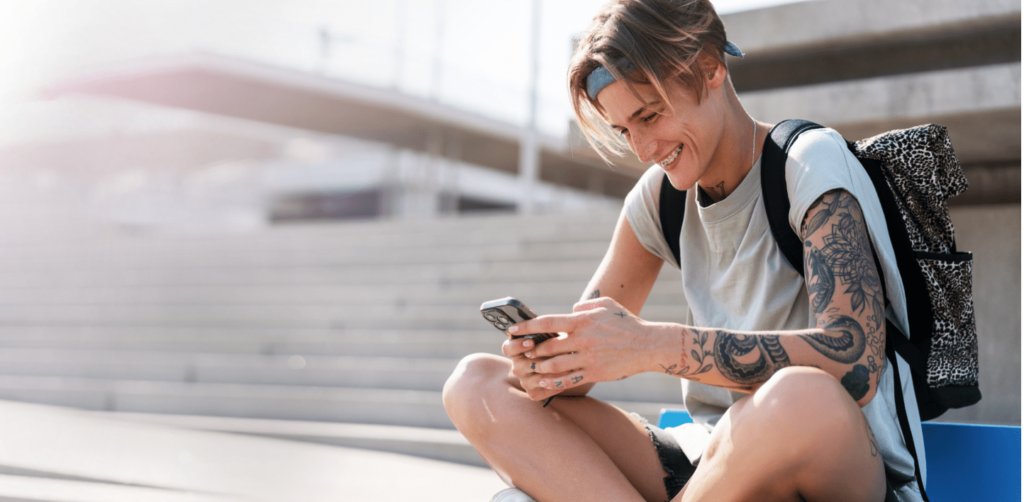 Person texting and smiling on outside on stairs